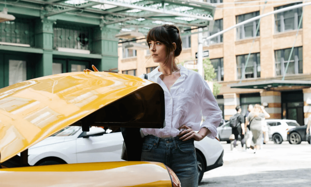 Cena de Amores Materialistas. A imagem mostra Dakota Johnson, que interpreta Lucy, ao lado de um táxi.